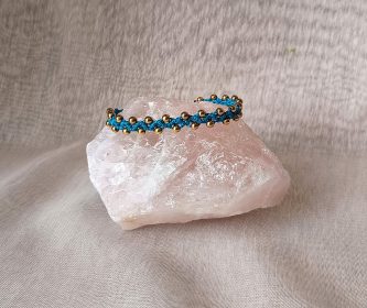 Détail du tissage point Zigo en relief sur un bracelet turquoise, perles dorées scintillantes, bijou fait main.