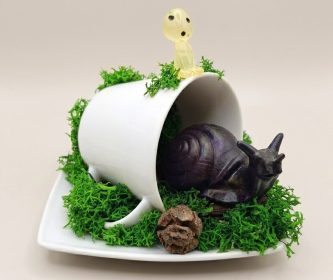 Gros plan sur un escargot en résine violet foncé scintillant sur de la mousse stabilisée.