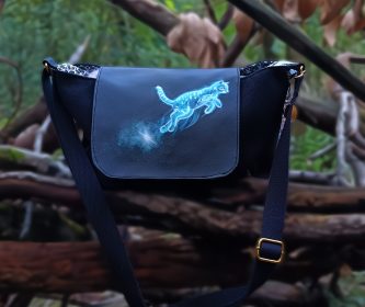 Sac Kréature collection Moon star, rabat simili cuir imprimé chat bleu bondissant. Vue posé sur un tronc d'arbre