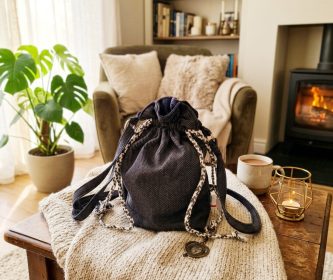 Le sac gris Orphéa posé sur un plaid dans un salon chaleureux près d'une cheminée, ambiance cosy.