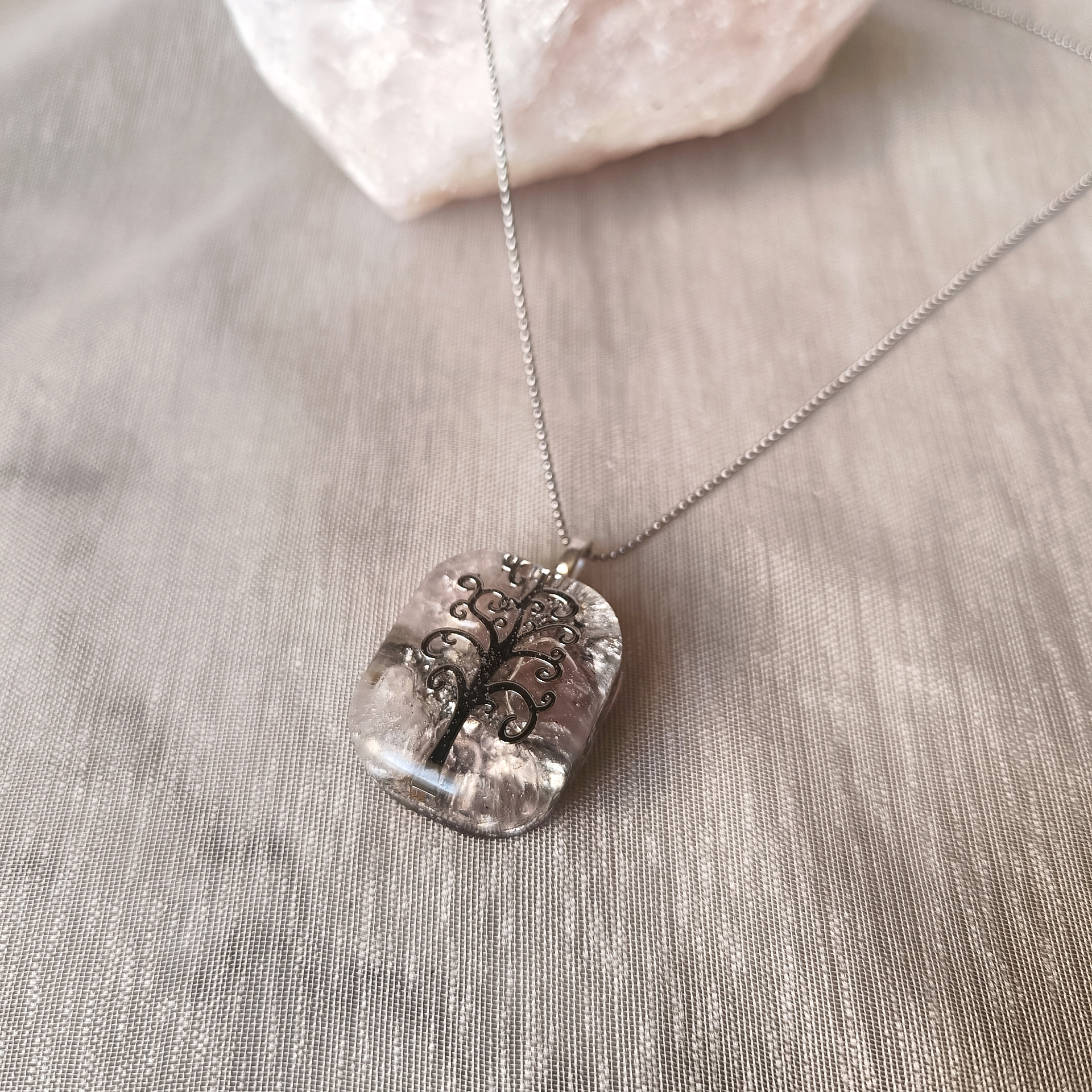 Gros plan sur le pendentif rectangulaire en résine transparente avec motif Arbre de Vie et éclats d'argent.