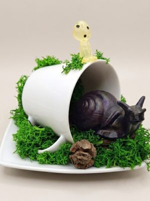 Gros plan sur un escargot en résine violet foncé scintillant sur de la mousse stabilisée.